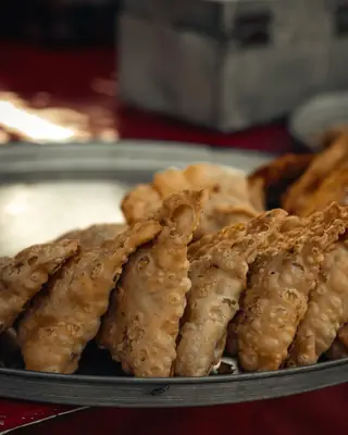 A tray of freshly fried snacks under a shop light